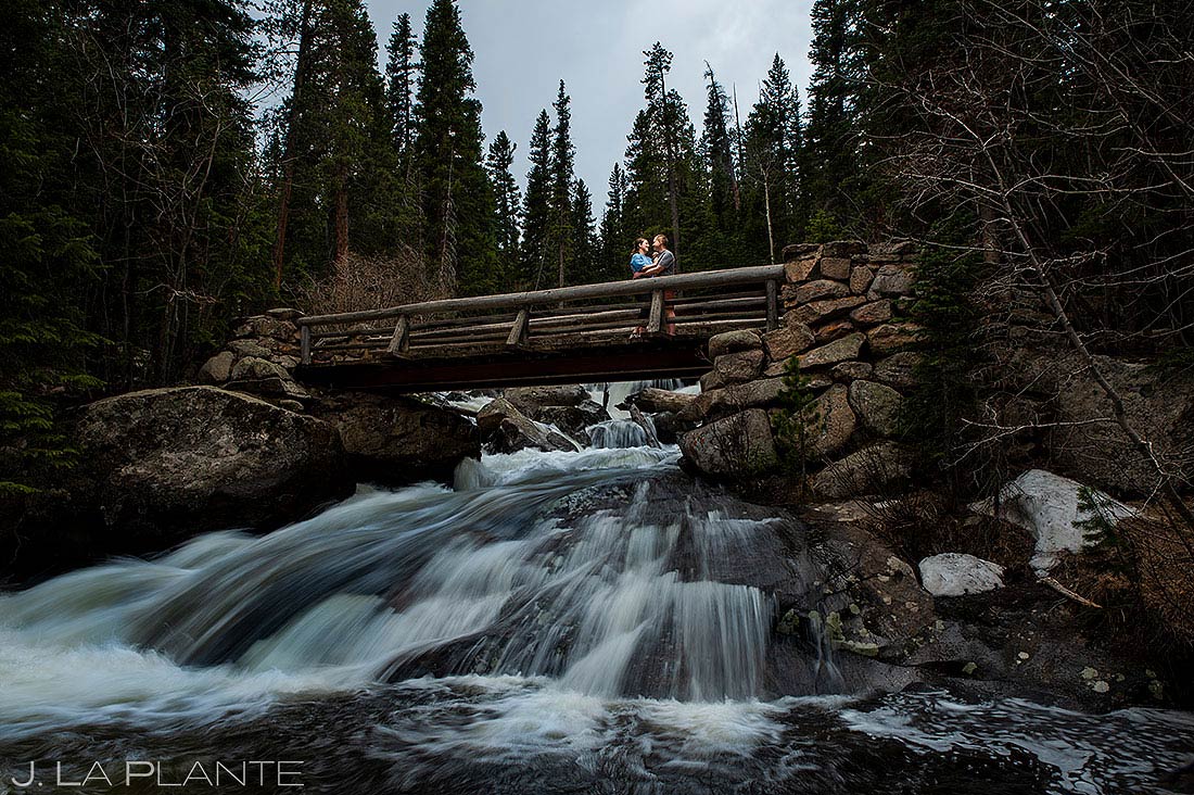 bride and groom to-be on bridge over waterfall at Ouzel Falls engagement session