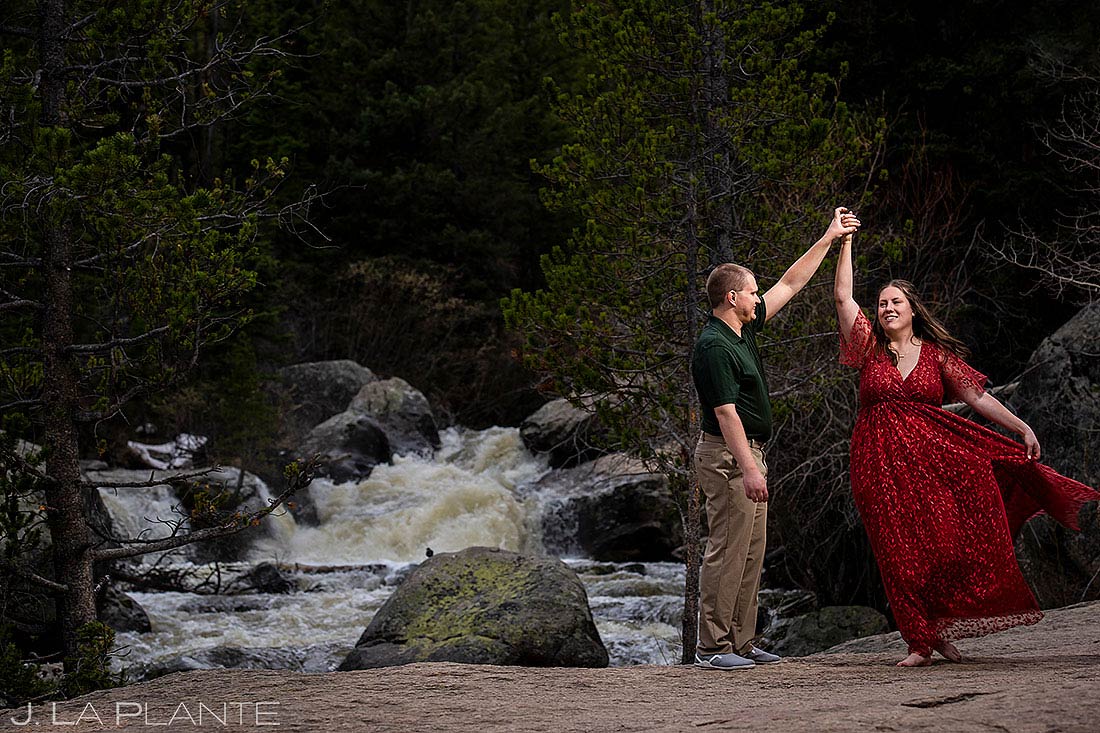 bride and groom dancing next to a mountain river