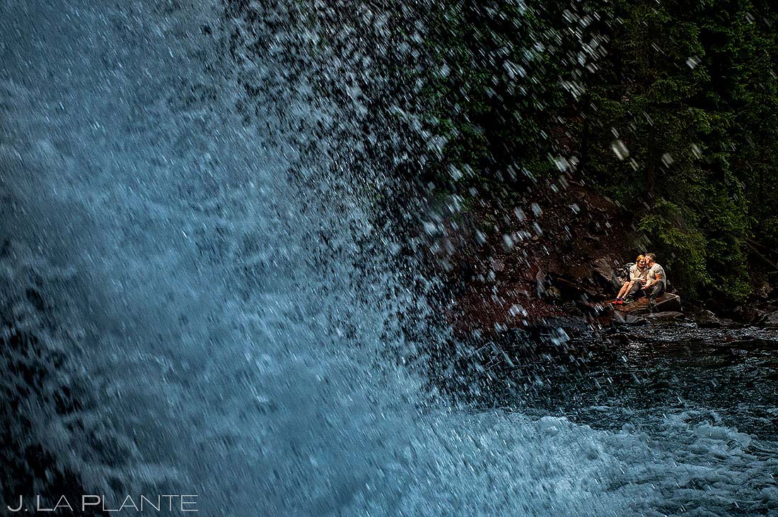 bride and groom kissing under mountain waterfall