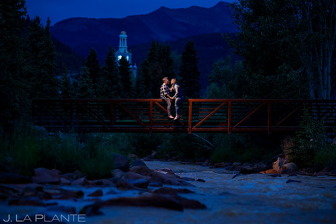 bride and groom sitting on bridge over river