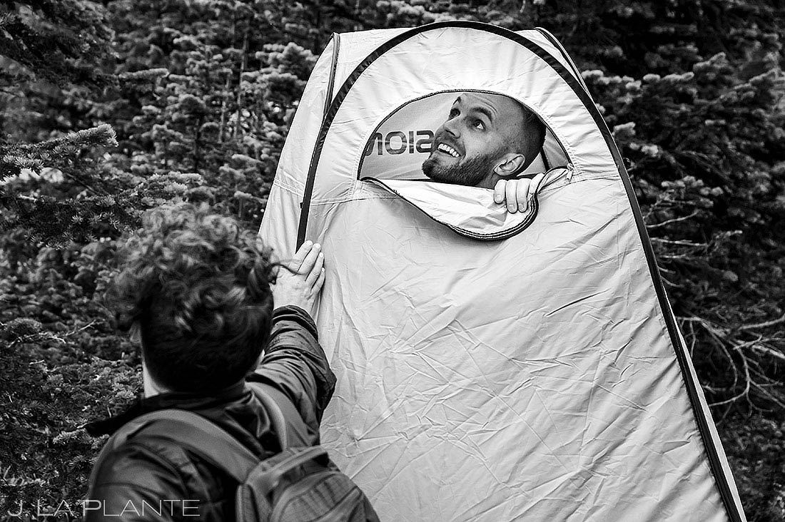 groom getting dressed in tent for Colorado adventure elopement