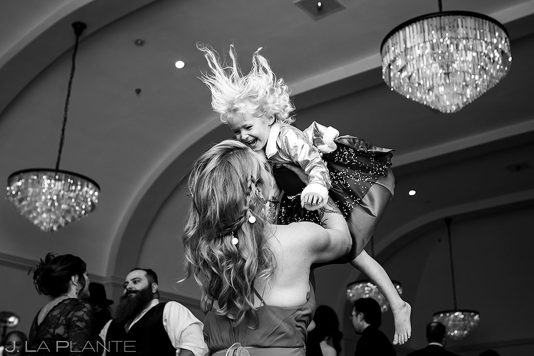 bridesmaid tossing her daughter up in the air on dance floor