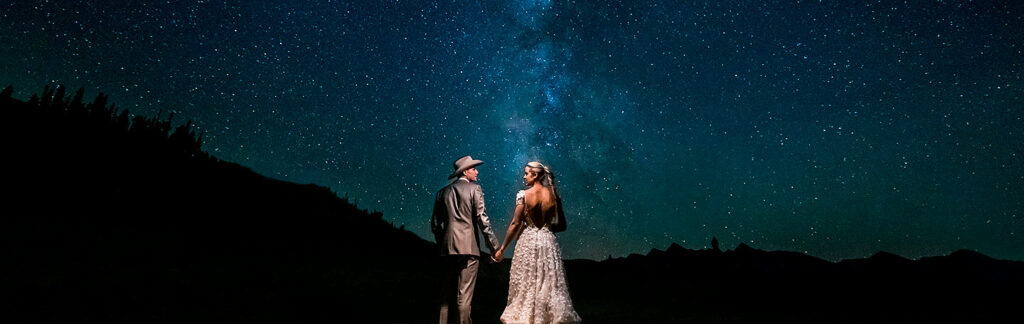 bride and groom holding hands under the Milky Way