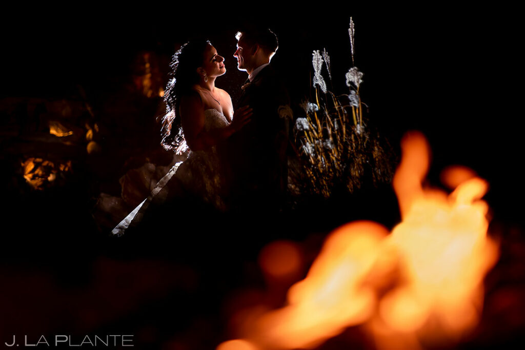 nighttime portrait of bride and groom by fireplace