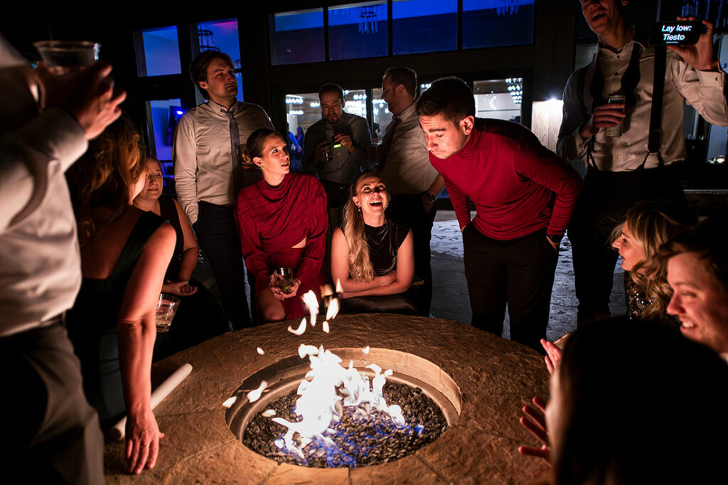 wedding guests hanging out by fire during reception