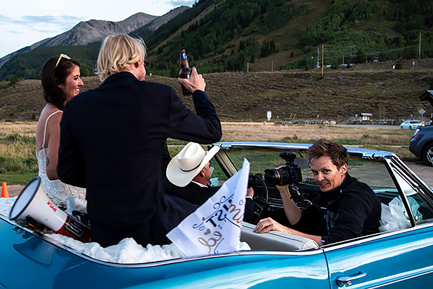 wedding photographer riding in convertible after ceremony