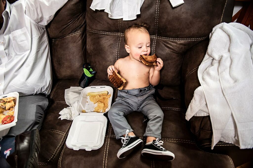 toddler eating two grilled cheese sandwiches at wedding