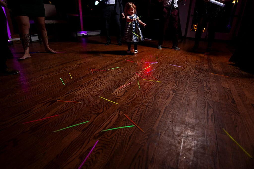 flower girl playing with glow sticks during wedding reception