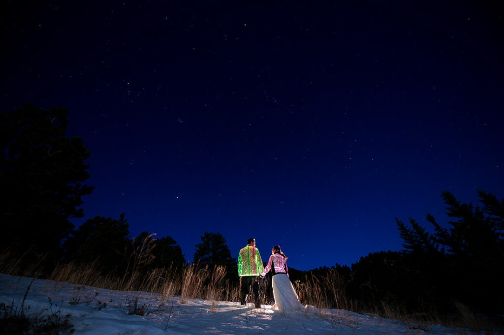 bride and groom with glow jackets under the stars