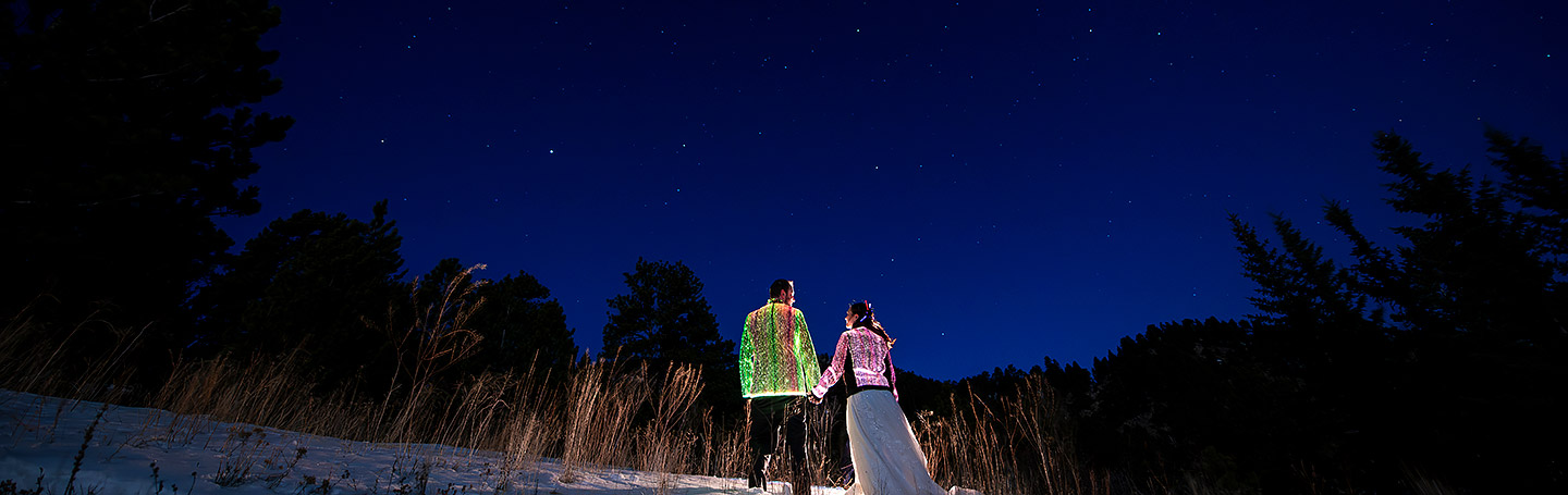 bride and groom with glow jackets under the stars