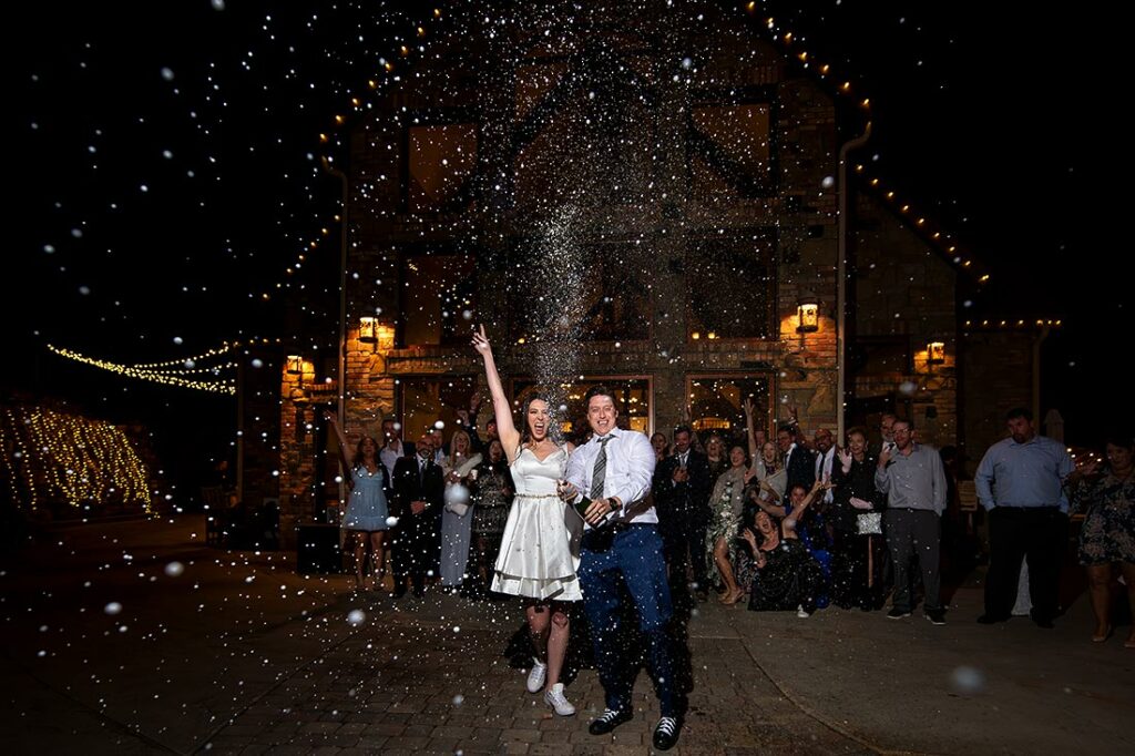 bride and groom popping champagne bottle at Estes Park wedding at Della Terra