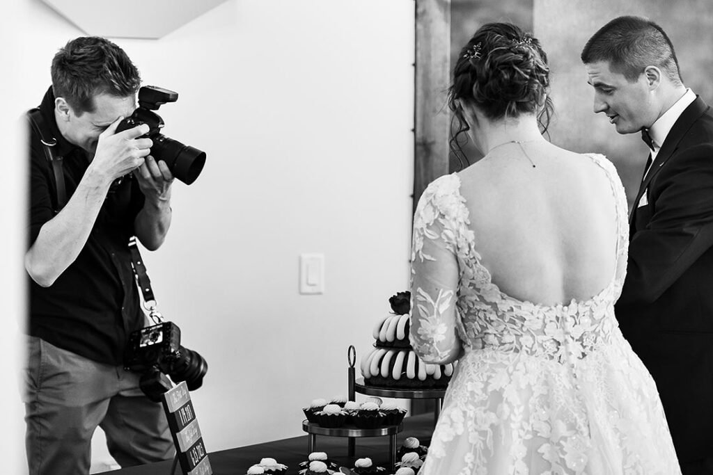 wedding photographer taking photos of bride and groom cutting the cake