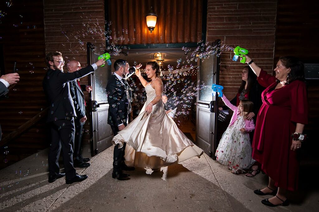 wedding photographer holding strobe light during bride and groom bubble send off